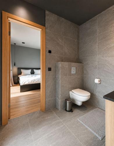 a bathroom with a toilet and a bedroom with a bed at SIA Green Guest House in Sigulda