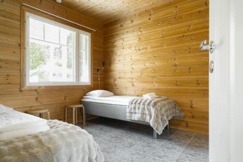 a bedroom with a tub in a wooden wall at Apartment A 3 Talja, Private Sauna By Lapland Host in Rovaniemi