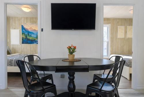 a dining room with a table and chairs and a tv at Relaxing Chalet Getaway with Spa Fireplace & BBQ in Saint-Tite-des-Caps