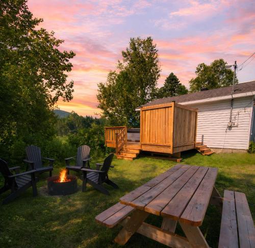 a backyard with a picnic table and a fire pit at Relaxing Chalet Getaway with Spa Fireplace & BBQ in Saint-Tite-des-Caps
