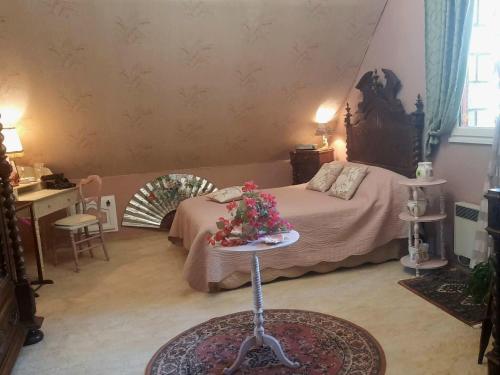a bedroom with a bed and a table with flowers on it at Chambre d hôte les bosquets in Caugé
