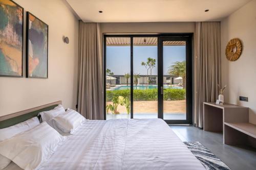 a bedroom with a bed and a view of a pool at Vanam at Sasan in Sasan Gir