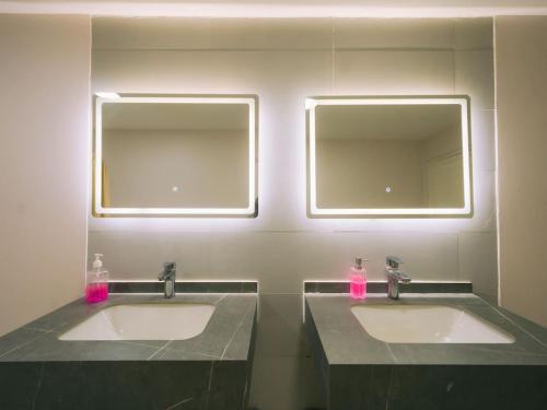 two sinks in a public bathroom with two mirrors at Palm Escape Farmhouse - By Seven Elements in Ras al Khaimah