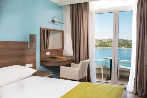 a hotel room with a bed and a desk and a window at Maistra Select Astarea Hotel in Mlini