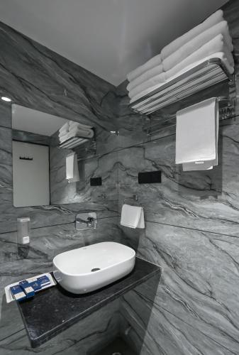 a bathroom with a sink and a marble wall at Hotel Sun Lorem, Ahmedabad in Ahmedabad