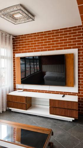 a living room with a brick wall with a tv at A Tóca in Rio de Janeiro