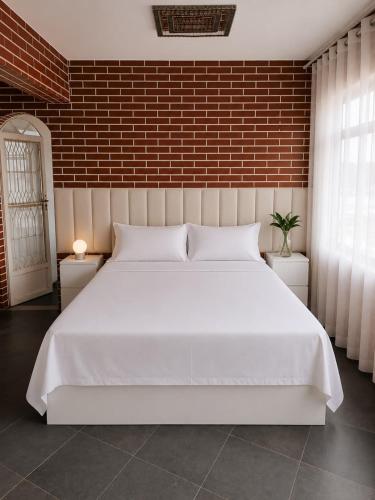 a large white bed in a bedroom with a brick wall at A Tóca in Rio de Janeiro