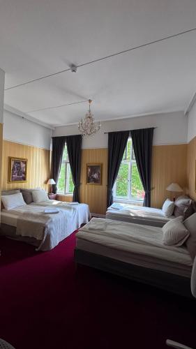 a large bedroom with two beds and a chandelier at Halden Grand hotell in Halden