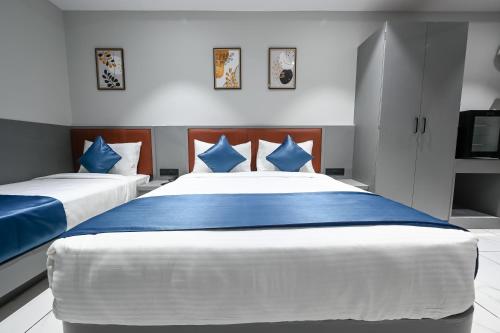 a bedroom with two beds with blue and white pillows at Hotel Sun Lorem, Ahmedabad in Ahmedabad