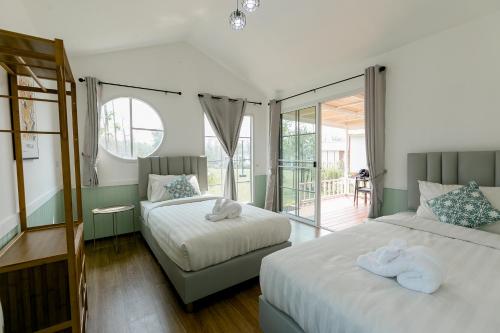 a bedroom with two beds and a balcony at ศรีคำน่านรีสอร์ท in Ban Muang Chang Tai