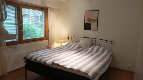a bedroom with a bed with a striped comforter and a window at Half Way in Kalaniemi