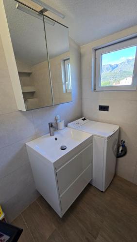 a white bathroom with a sink and a window at Studios Ilic in Seline