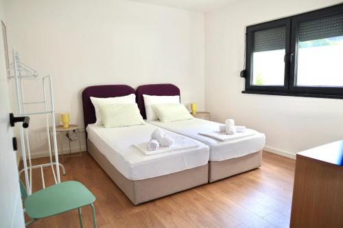 a white bed in a room with a window at Villa Vincek in Mostar