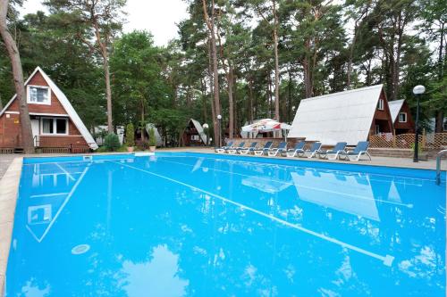 a swimming pool with chairs and a house at Gryf Domki Pobierowo in Pobierowo