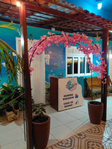 an entrance to a aquarium with pink flowers and plants at Hostel e Pousada Blue Lagoon in Abraão