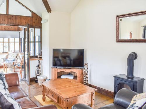 a living room with a tv and a wood stove at Riverbank Cottage-Uk42229 in Low Borrowbridge