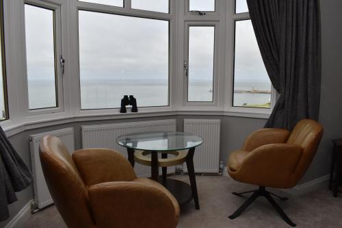 a room with two chairs and a table and windows at The Seacliffe - Whitby in Whitby