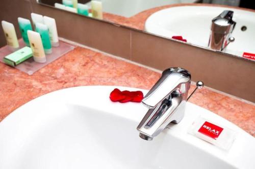 a bathroom sink with a faucet in front of a mirror at Relax Hotel Airport Nouasseur in Nouaseur