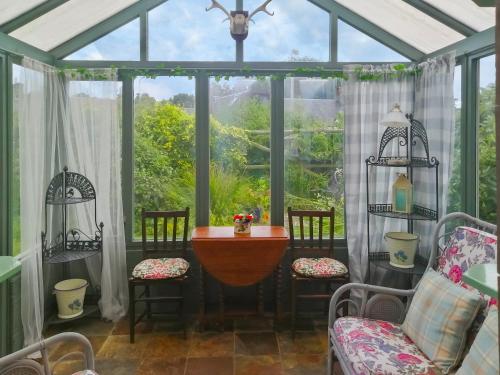 a conservatory with a table and chairs and a window at Ivy Cottage in Crieff
