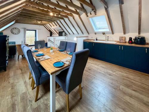 a dining room table with chairs and a kitchen at Wellness Cottage At Tomnauld Farm in Pitlochry