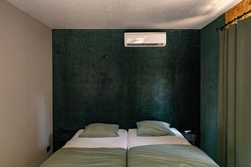 a bedroom with two beds and a green wall at Woodboxcabins - Campinggroenpark in Zele
