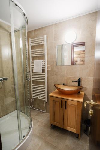ein Badezimmer mit einem Holzwaschbecken und einer Dusche in der Unterkunft Abigarrado in Rucăr