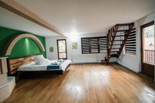 ein Schlafzimmer mit grünen Wänden, einem Bett und einer Treppe in der Unterkunft Abigarrado in Rucăr