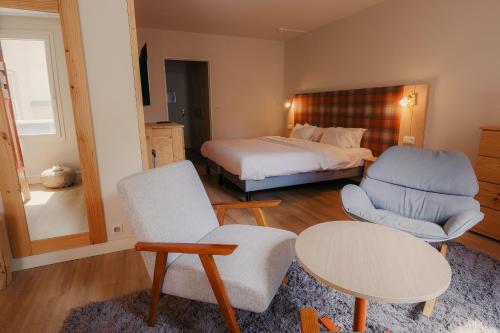 a bedroom with a bed and a table and chairs at Hôtel Le Refuge des Sources in Digne-les-Bains