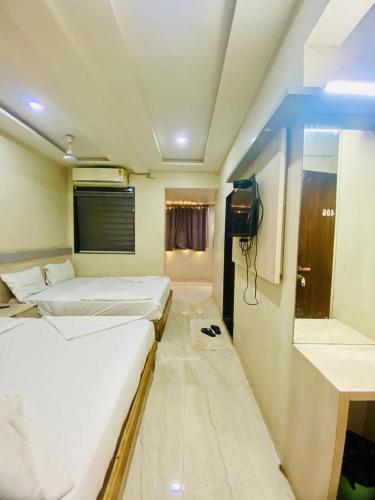 a room with two beds and a television in it at Hotel Bhiwandi Palace Nashik Highway Rd in Bhiwandi