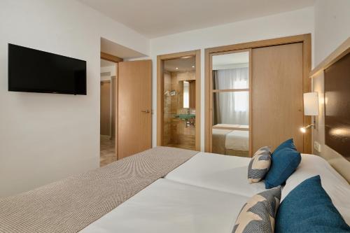 a bedroom with a large bed with a flat screen tv at Grupotel Dunamar in Can Picafort