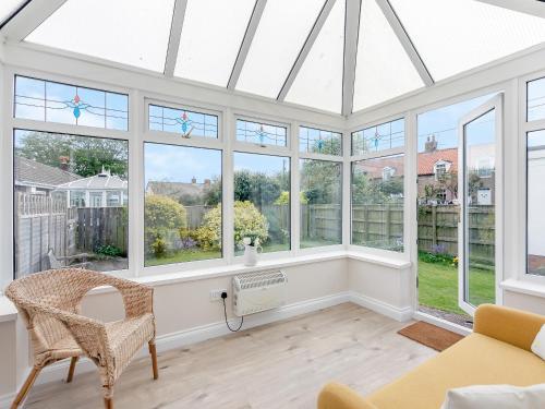 a conservatory with windows and a table and chair at Seashell Haven in Beadnell
