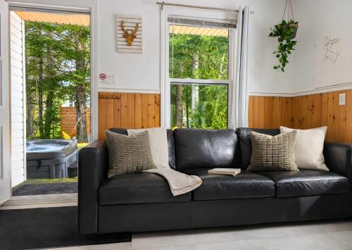 a black leather couch in a living room at Charlevoix spa bbq fire & nature in Saint-Tite-des-Caps