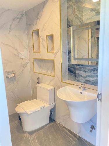 a bathroom with a sink and a toilet and a mirror at Monanza Hotel in Ban Thung Prong