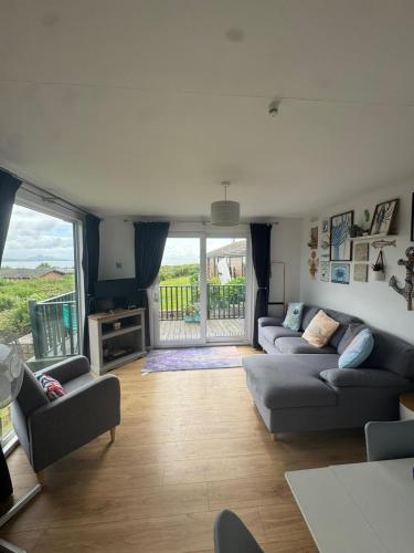 a living room with two couches and a balcony at Pine Lodge @Puffin Lodges in Chwilog
