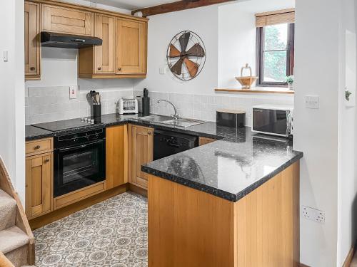 a kitchen with wooden cabinets and a black counter top at Brook Cottage - Ukc9515 in Beaworthy
