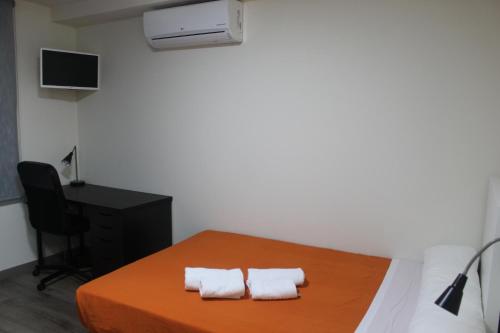una camera con un letto, una scrivania e due asciugamani di Europa House Village a San Vicente del Raspeig