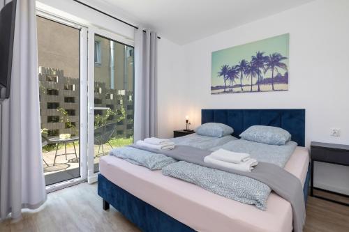 a bedroom with two beds and a large window at Apartamenty pod Modrzewiem in Ustronie Morskie