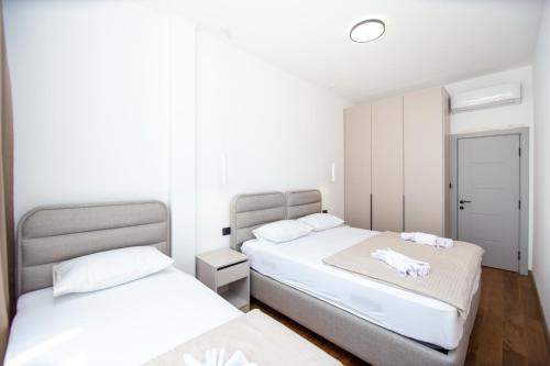 two beds in a room with white walls at Lastva Cozy apartment in Prijevor
