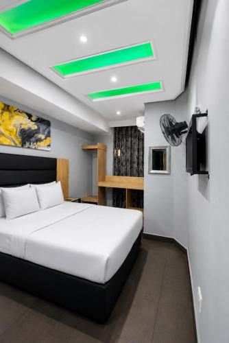 a bedroom with a white bed and a green ceiling at Hotel Metro Lodge Beach in Durban