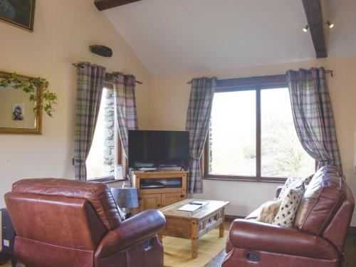 a living room with two leather chairs and a flat screen tv at River View Cottage-Uk42226 in Low Borrowbridge