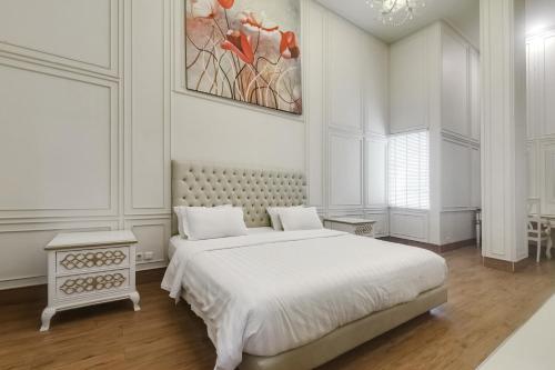 a white bedroom with a bed and a painting on the wall at Onih Hotel in Bogor