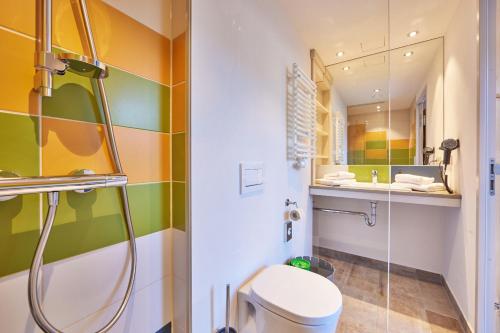a bathroom with a shower and a toilet and a sink at Explorer Hotel Bayrischzell in Bayrischzell