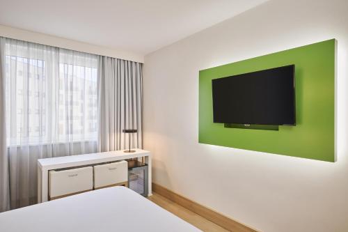 a bedroom with a bed and a tv on a wall at NH Berlin Potsdamer Platz in Berlin