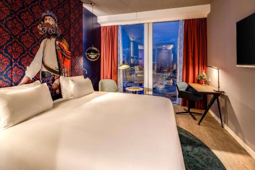 a hotel room with a large white bed and a window at nhow Amsterdam Rai in Amsterdam