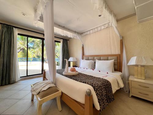 a bedroom with a large bed and a large window at Diani Reef Beach Resort & Spa - Your Beachfront Bliss Awaits in Diani Beach