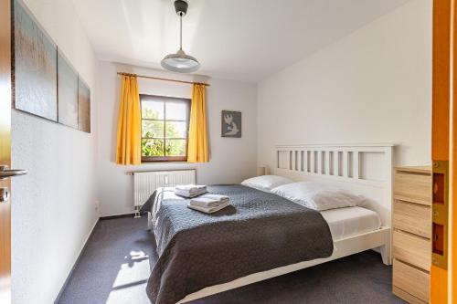 a bedroom with a bed and a window with orange curtains at Henriette in Ahrenshoop