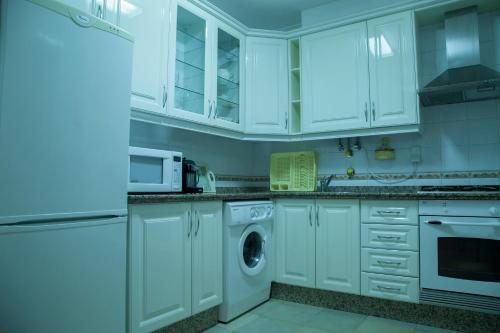 - une cuisine avec des placards blancs et un lave-linge/sèche-linge dans l'établissement Our Little House, à Vila Real de Santo António
