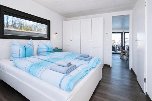 ein weißes Schlafzimmer mit einem großen Bett und blauen Kissen in der Unterkunft Floatinghouse LP16 in Braunsbedra