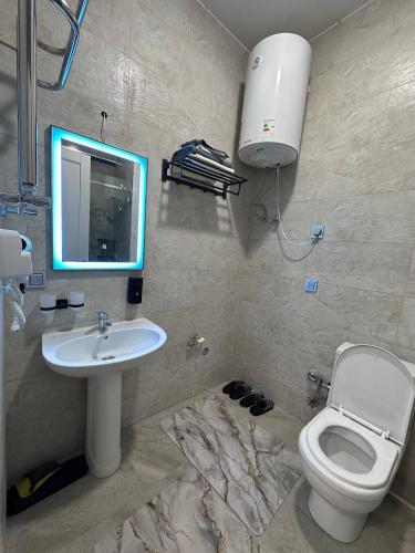 a bathroom with a sink and a toilet and a mirror at Chorvoq Darvozasi touristic complex in Chorwoq