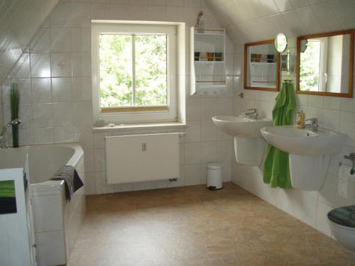 a bathroom with two sinks and a tub and a window at Villa Mary in Lychen